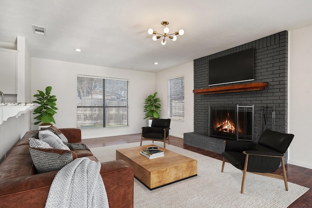 living room featuring visible vents, a fireplace, baseboards, and wood finished floors