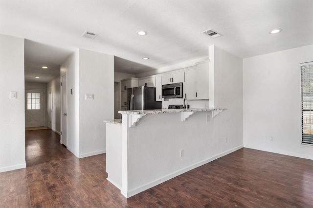926 Harber Ave, Grapevine, TX 76051 - kitchen with stainless steel appliances, a peninsula, a breakfast bar, white cabinets, and light stone countertops