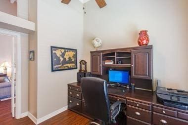 office featuring a towering ceiling, baseboards, ceiling fan, and dark wood-style flooring