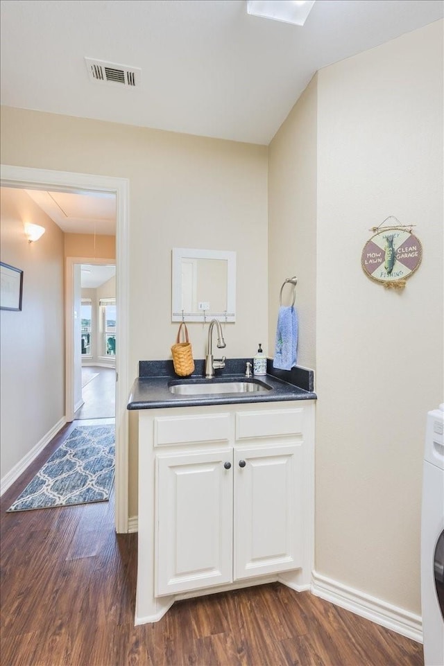 interior space featuring dark countertops, visible vents, dark wood-type flooring, washer / clothes dryer, and a sink