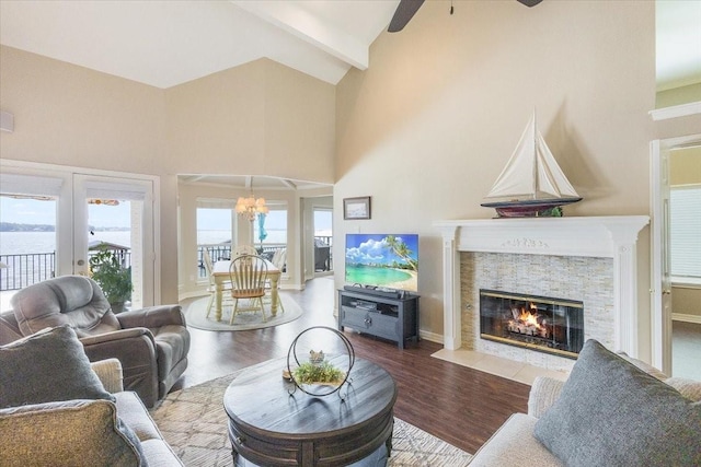 living area with beam ceiling, wood finished floors, a fireplace, and high vaulted ceiling