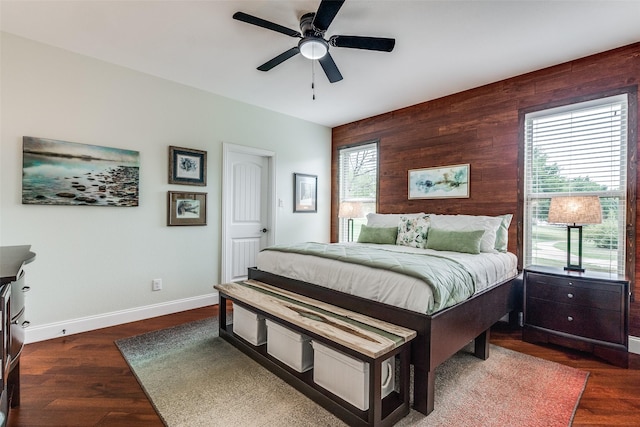 bedroom featuring baseboards, wood finished floors, a ceiling fan, and wood walls