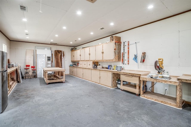 garage with a workshop area, recessed lighting, visible vents, and freestanding refrigerator