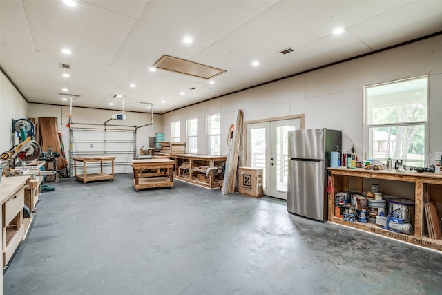 garage with a workshop area, visible vents, and freestanding refrigerator