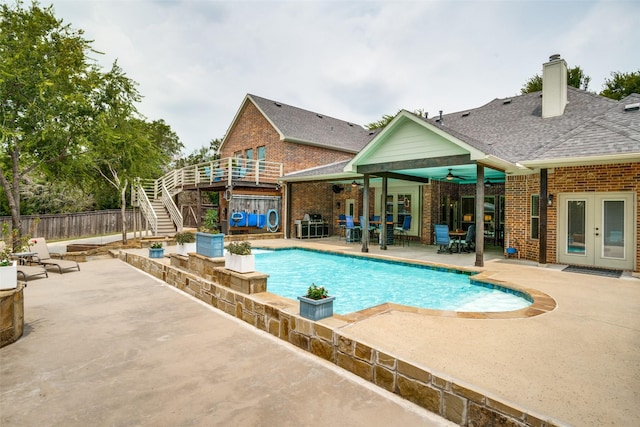 view of swimming pool with a ceiling fan, fence, french doors, stairs, and a patio area