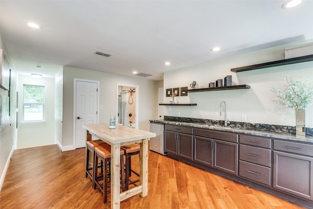 kitchen with visible vents, light wood-style flooring, open shelves, a sink, and dishwashing machine