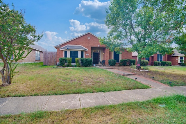 view of front of property featuring a front yard, fence, and brick siding