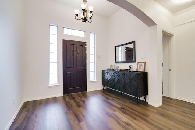 foyer with baseboards, arched walkways, and wood finished floors