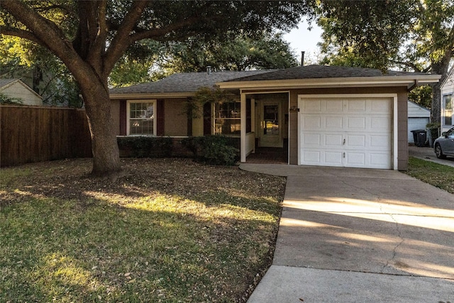 ranch-style house featuring a front yard, fence, driveway, roof with shingles, and a garage