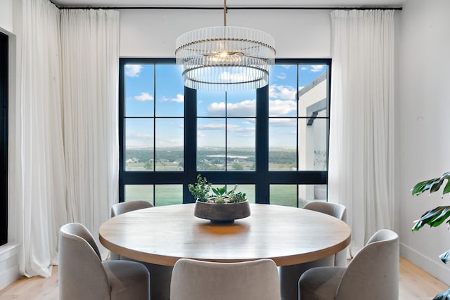 dining room with an inviting chandelier, light wood-style floors, and baseboards