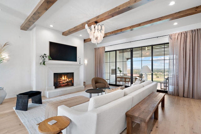 living area with a glass covered fireplace, beam ceiling, recessed lighting, and wood finished floors