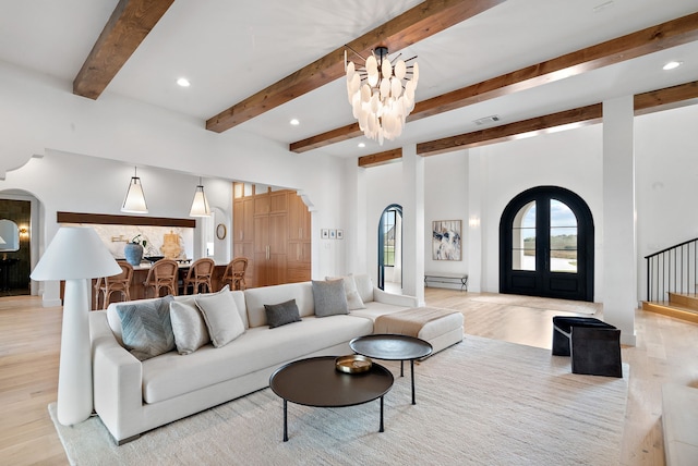 living area featuring light wood finished floors, visible vents, recessed lighting, arched walkways, and a notable chandelier