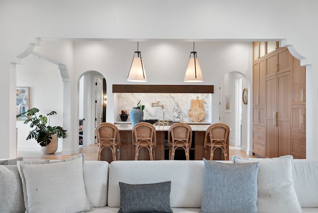 living area with light wood-style floors, arched walkways, and baseboards