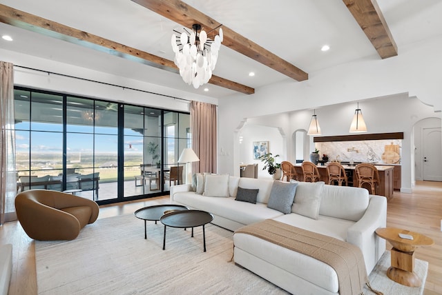 living room featuring recessed lighting, light wood-type flooring, arched walkways, and a notable chandelier