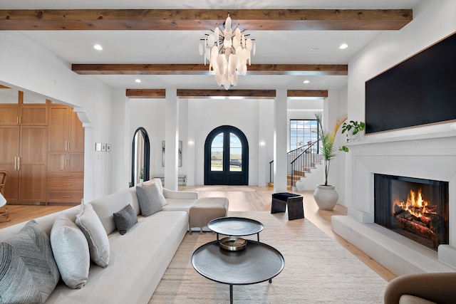 living room with a warm lit fireplace, recessed lighting, arched walkways, light wood finished floors, and stairs