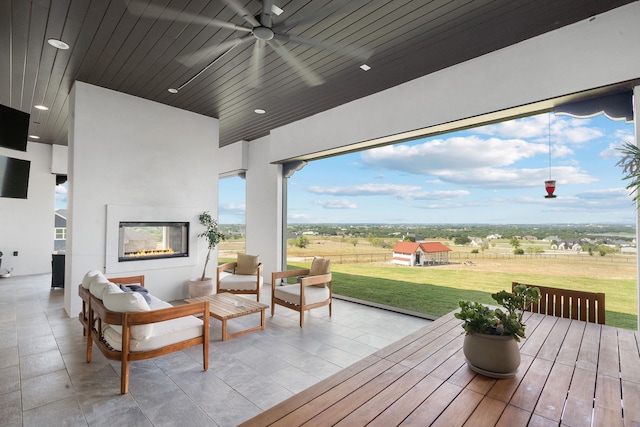 deck featuring a patio area, a lawn, a ceiling fan, and an outdoor living space with a fireplace