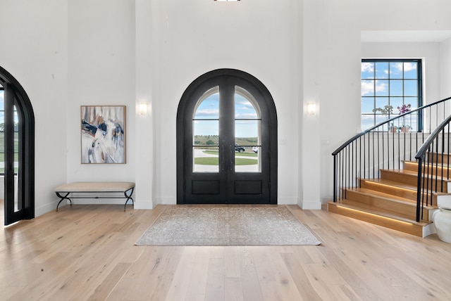 foyer entrance featuring arched walkways, wood finished floors, and a towering ceiling