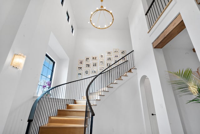 staircase with a high ceiling and a chandelier