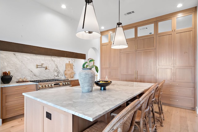 kitchen featuring visible vents, light wood-type flooring, high end stainless steel range oven, and light stone countertops