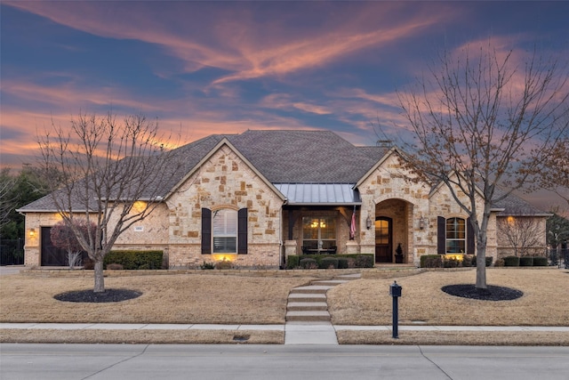 french provincial home featuring a garage, a standing seam roof, a porch, a shingled roof, and metal roof