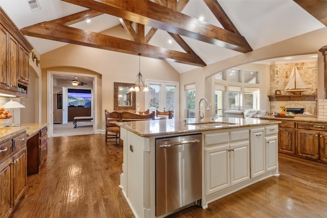 kitchen with a sink, stainless steel dishwasher, open floor plan, wood finished floors, and arched walkways