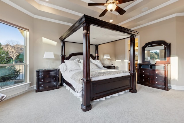 carpeted bedroom featuring baseboards, a ceiling fan, a tray ceiling, and ornamental molding