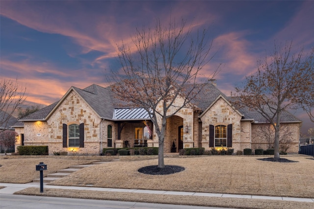 french country style house with metal roof, brick siding, covered porch, and a standing seam roof