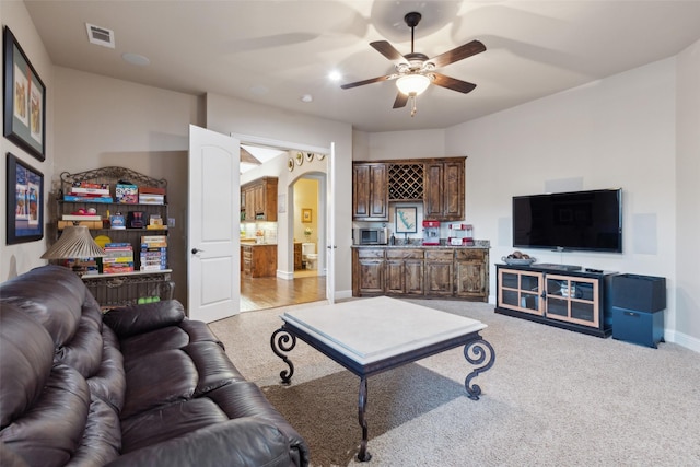 living area featuring visible vents, baseboards, ceiling fan, carpet flooring, and arched walkways