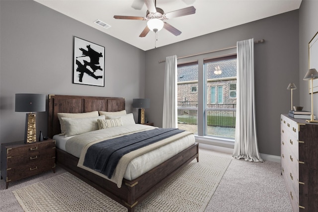 carpeted bedroom featuring visible vents, multiple windows, baseboards, and ceiling fan