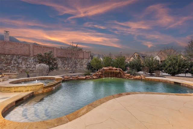 pool at dusk featuring a patio, a pool with connected hot tub, and fence