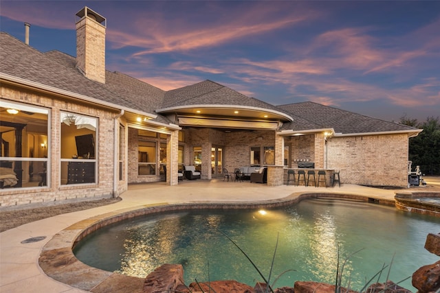 view of swimming pool featuring a patio area, a pool with connected hot tub, and outdoor dry bar