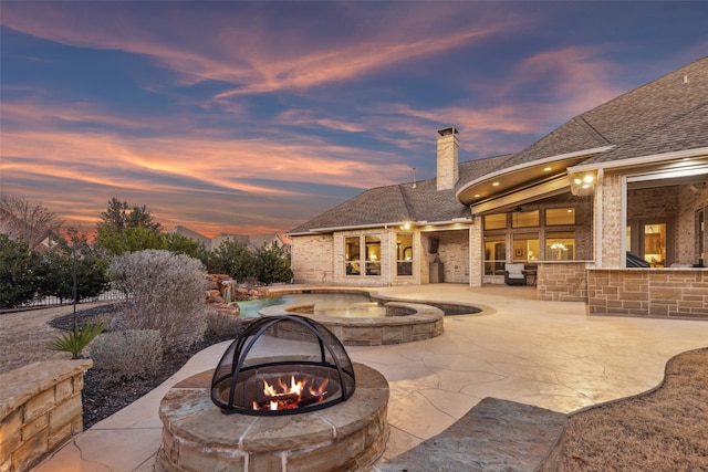 view of patio / terrace with outdoor dry bar, a pool with connected hot tub, and a fire pit