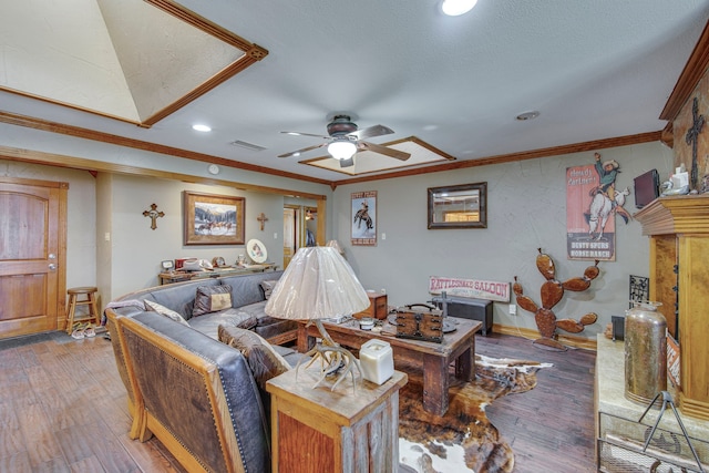 living area featuring wood finished floors, baseboards, visible vents, ceiling fan, and ornamental molding