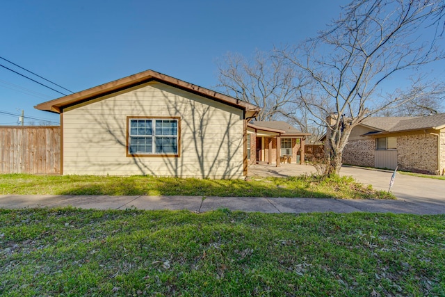 view of home's exterior featuring fence, a lawn, and driveway