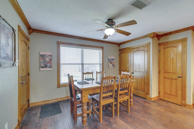 dining area featuring visible vents, baseboards, ornamental molding, wood finished floors, and a textured ceiling