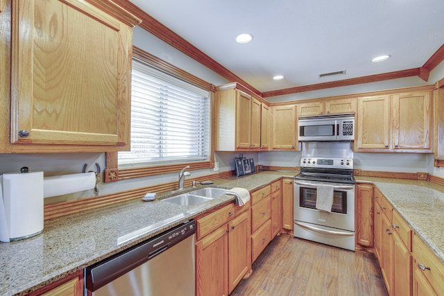 kitchen with visible vents, a sink, stainless steel appliances, crown molding, and light wood-type flooring