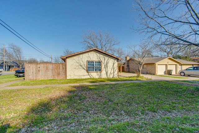 view of side of property with a yard, a garage, and fence