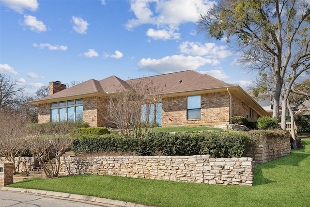 view of home's exterior featuring brick siding, a lawn, a chimney, and a shingled roof