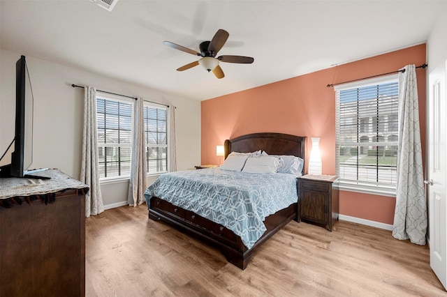 bedroom featuring multiple windows, baseboards, and light wood finished floors