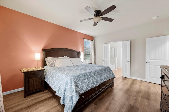 bedroom with connected bathroom, baseboards, light wood-style floors, and ceiling fan