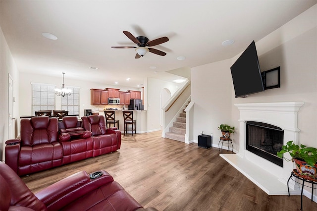 living area with stairway, wood finished floors, baseboards, and a fireplace with raised hearth