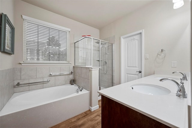 full bathroom featuring a sink, wood finished floors, a shower stall, double vanity, and a bath