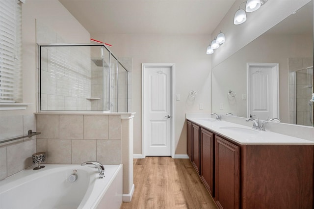 bathroom with double vanity, a bath, tiled shower, and a sink