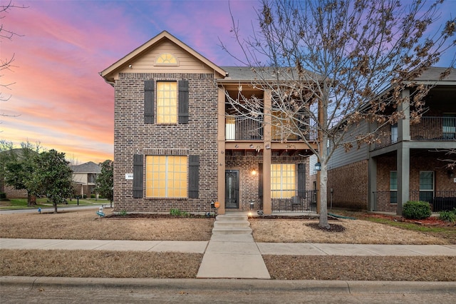 traditional-style home featuring a balcony and brick siding