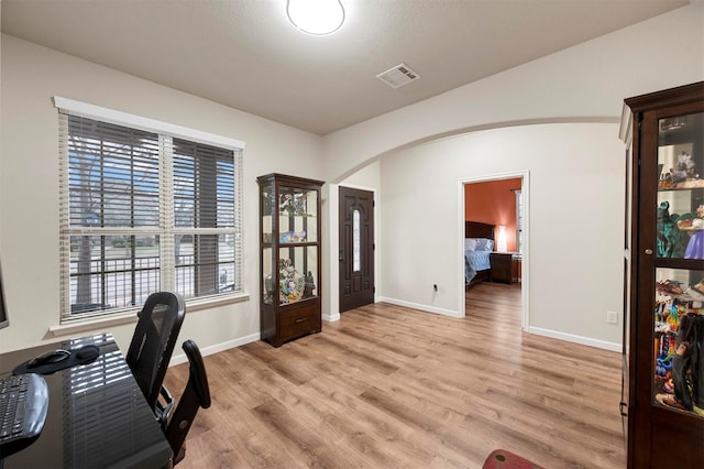 office space featuring visible vents, arched walkways, light wood-style floors, and baseboards