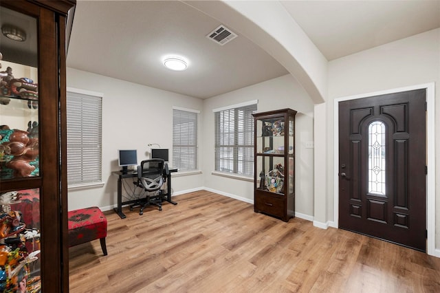 entryway featuring visible vents, arched walkways, light wood-style floors, and baseboards