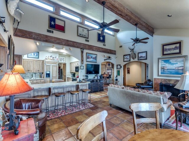 living area with visible vents, arched walkways, high vaulted ceiling, and beam ceiling