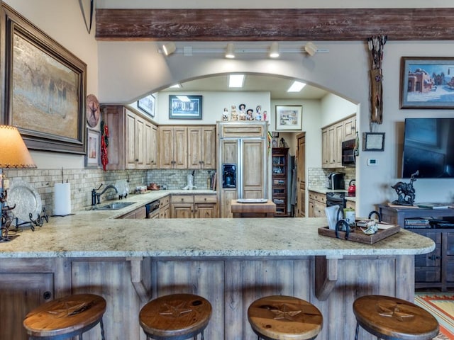 kitchen featuring black appliances, a sink, backsplash, arched walkways, and a peninsula