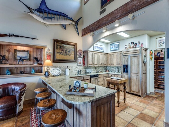 kitchen featuring paneled fridge, a sink, backsplash, a peninsula, and a breakfast bar area