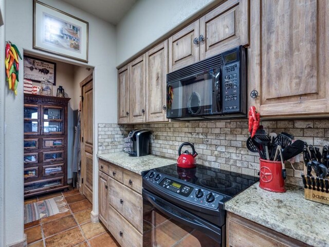 kitchen featuring decorative backsplash, black appliances, and light stone countertops